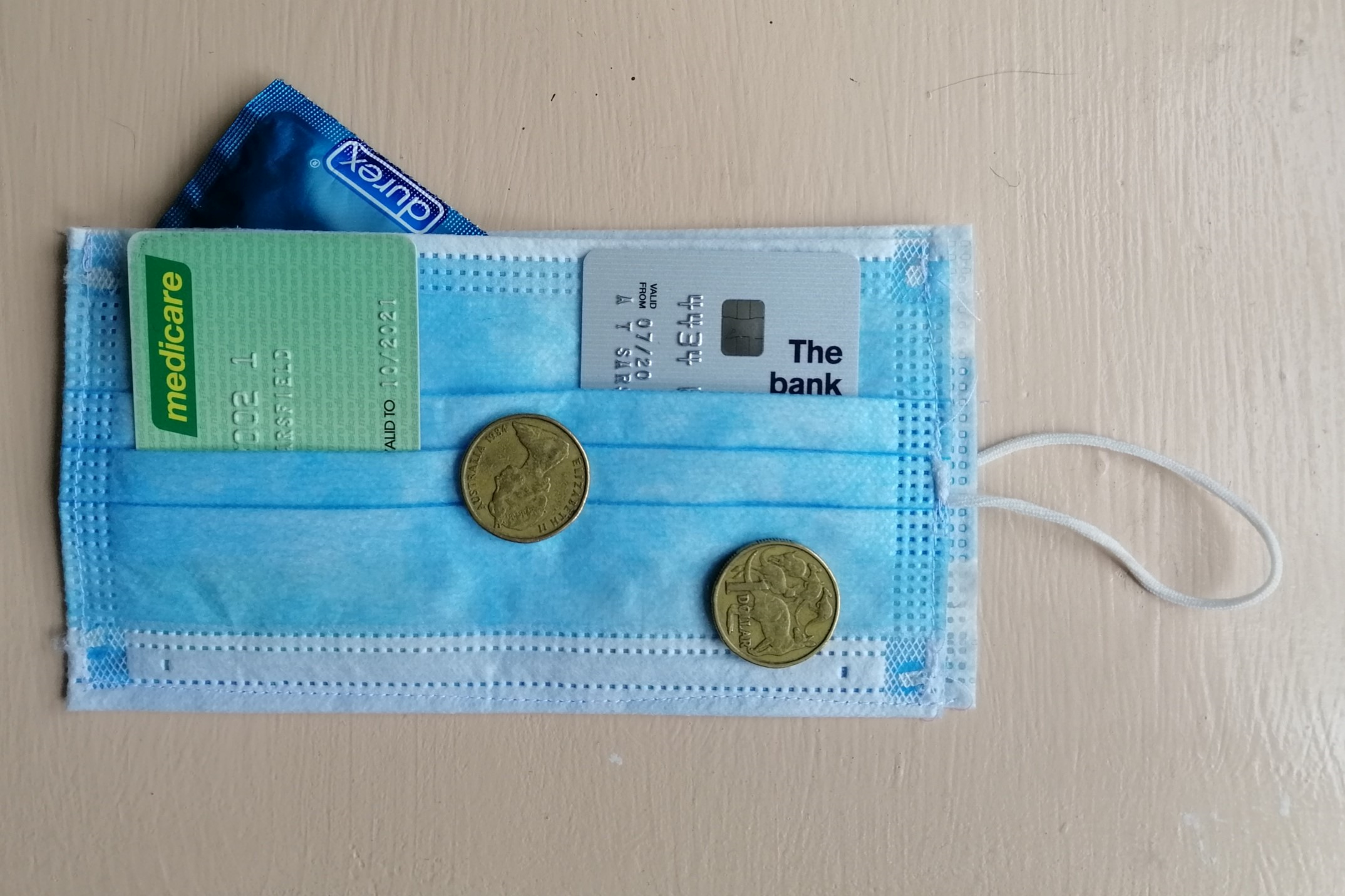 A wallet made from a surgical mask with cards and coins in it